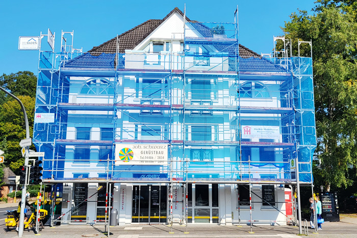 Ein Geschäftsgebäude, dessen Fassade renoviert wird. Das Gebäude ist von einem Gerüst eingehüllt.